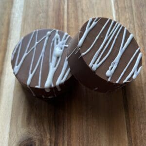 Two chocolate treats with white drizzle.