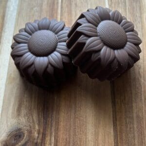 Chocolate sunflower-shaped treats on wooden surface.