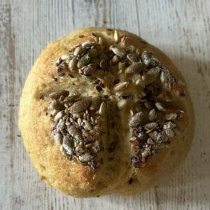 Seeded bread roll on wooden table.