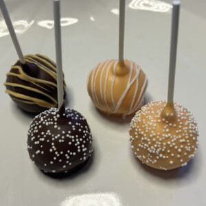 Four decorated cake pops on a plate.