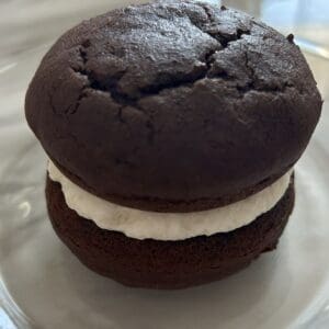Chocolate whoopie pie with creamy filling on a glass plate.